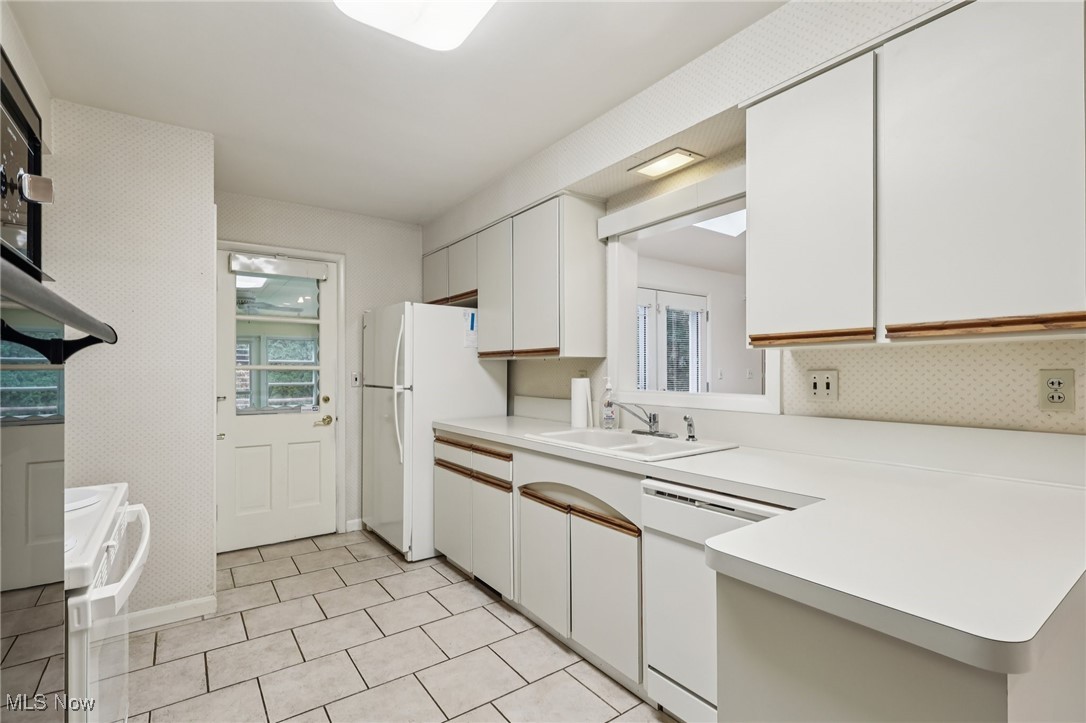 33300 South Woodland Road Cleveland, OH 44124 - Photo 24 of 50 Kitchen with light countertops, white appliances, white cabinets, a peninsula, and light tile patterned floors