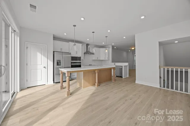 a large white kitchen with kitchen island a sink a stove a refrigerator and a cabinets