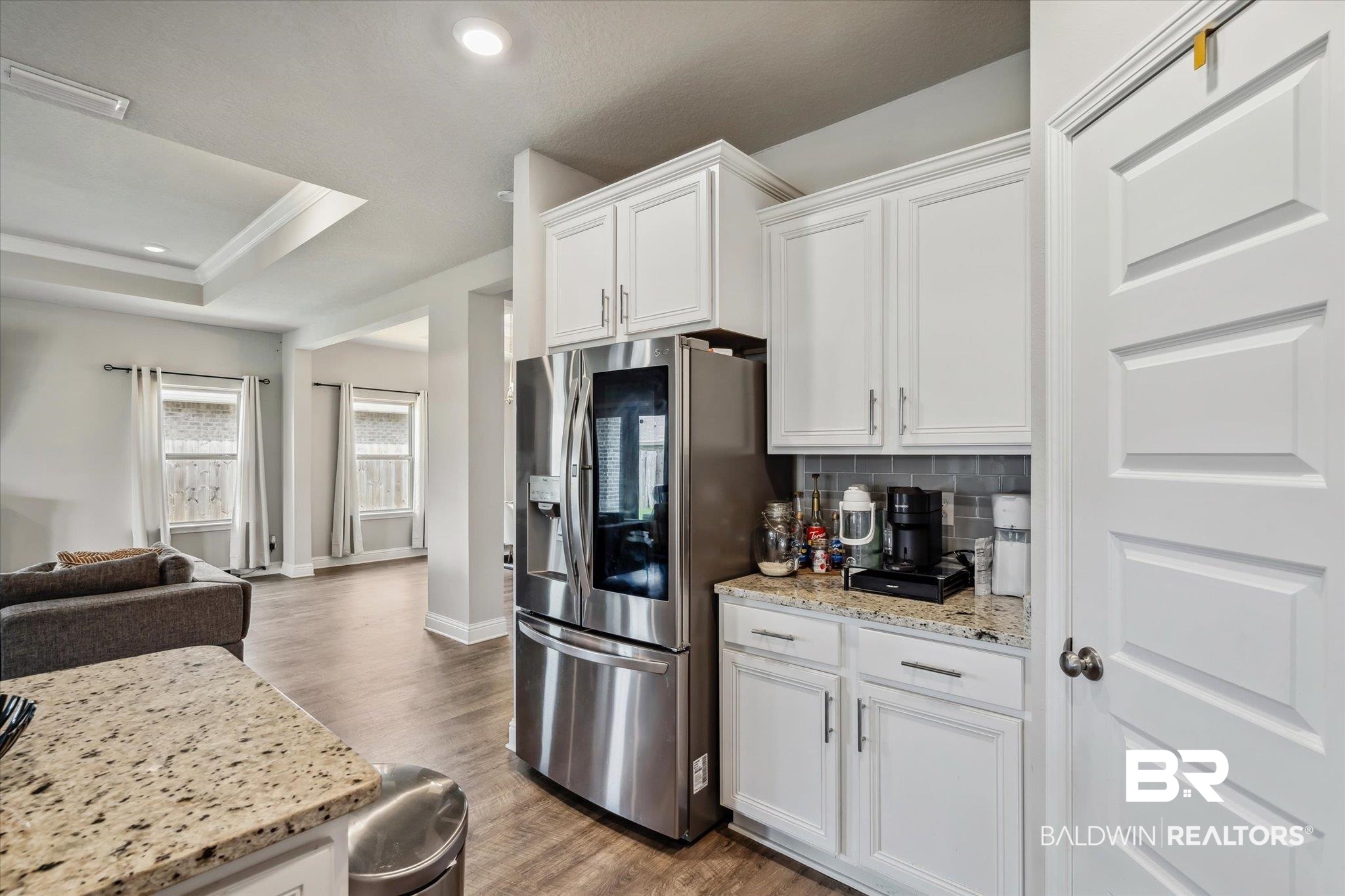 10501 Loamy Avenue Mobile, AL 36695 - Photo 9 of 30 Kitchen featuring wood-type flooring, tasteful backsplash, stainless steel refrigerator with ice dispenser, white cabinets, and a raised ceiling