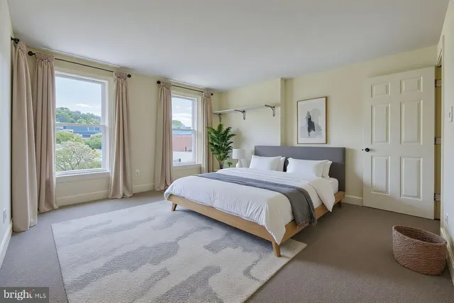 a large bed sitting in a bedroom next to a window and a larger closet