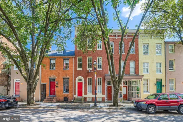 a front view of a building with large trees