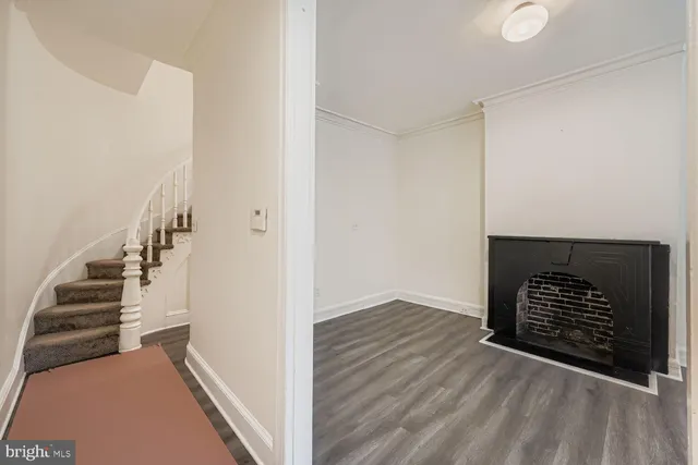a view of an empty room with wooden floor and stairs