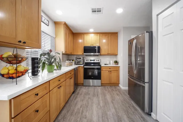 a kitchen with stainless steel appliances a refrigerator sink and wooden cabinets