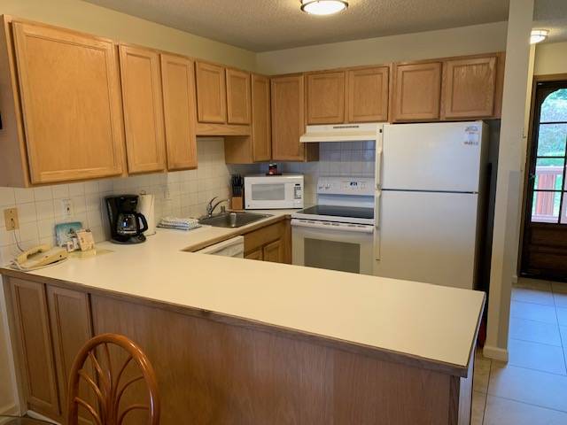 3411 Wilcox Road, Unit 110 Lihue, HI 96766 - Photo 5 of 12 a kitchen with granite countertop a refrigerator sink stove and cabinets