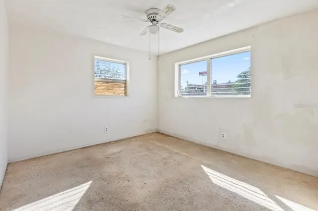 an empty room with windows and fan