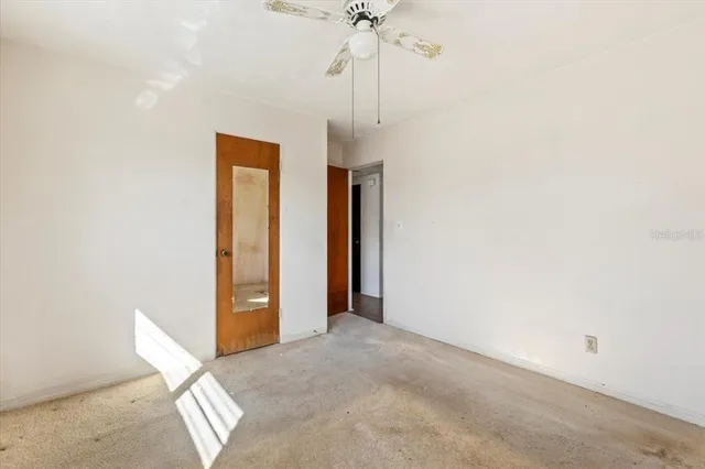 an empty room with a chandelier fan and a window