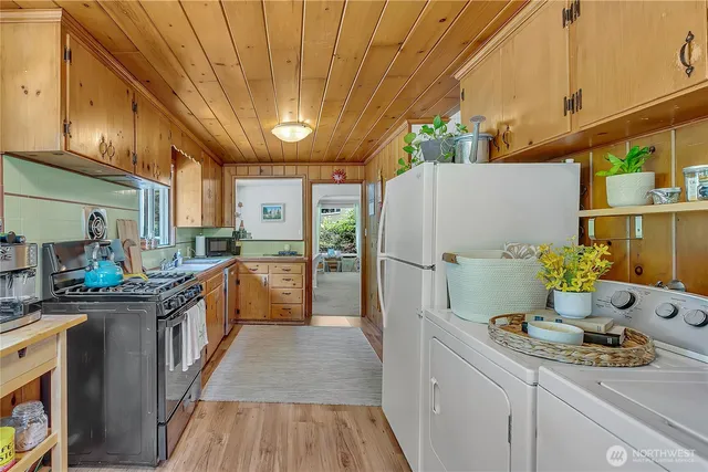 a kitchen with stainless steel appliances a refrigerator a sink and wooden floors