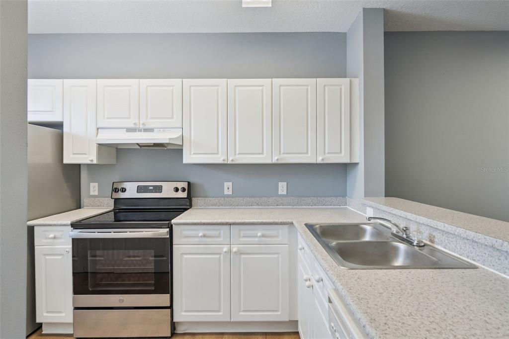 720 Celebration Avenue, Unit 220 Celebration, FL 34747 - Photo 6 of 45 a kitchen with granite countertop a sink stove and cabinets