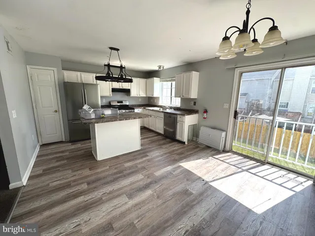 a kitchen with stainless steel appliances granite countertop a kitchen island hardwood floor sink and stove