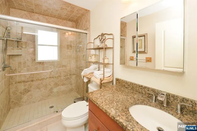 a bathroom with a granite countertop sink mirror vanity and toilet