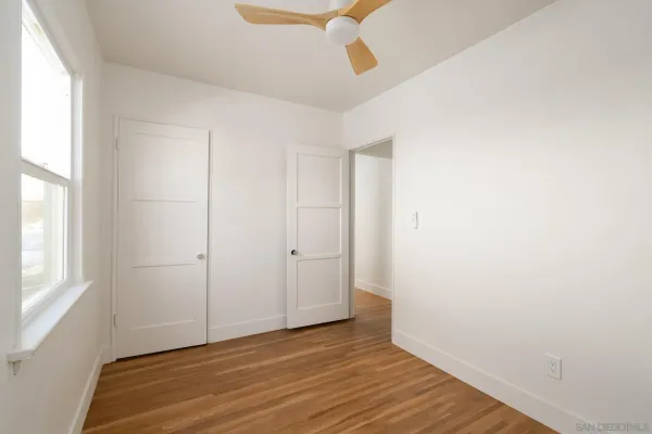 a view of an empty room with wooden floor and a window