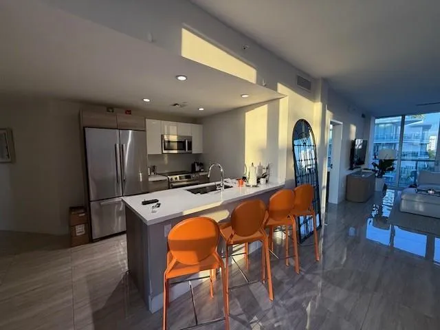 a kitchen with stainless steel appliances granite countertop a refrigerator a stove a sink a dining table and chairs with wooden floor