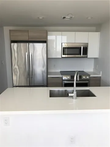 a kitchen with stainless steel appliances granite countertop a refrigerator a sink and a stove