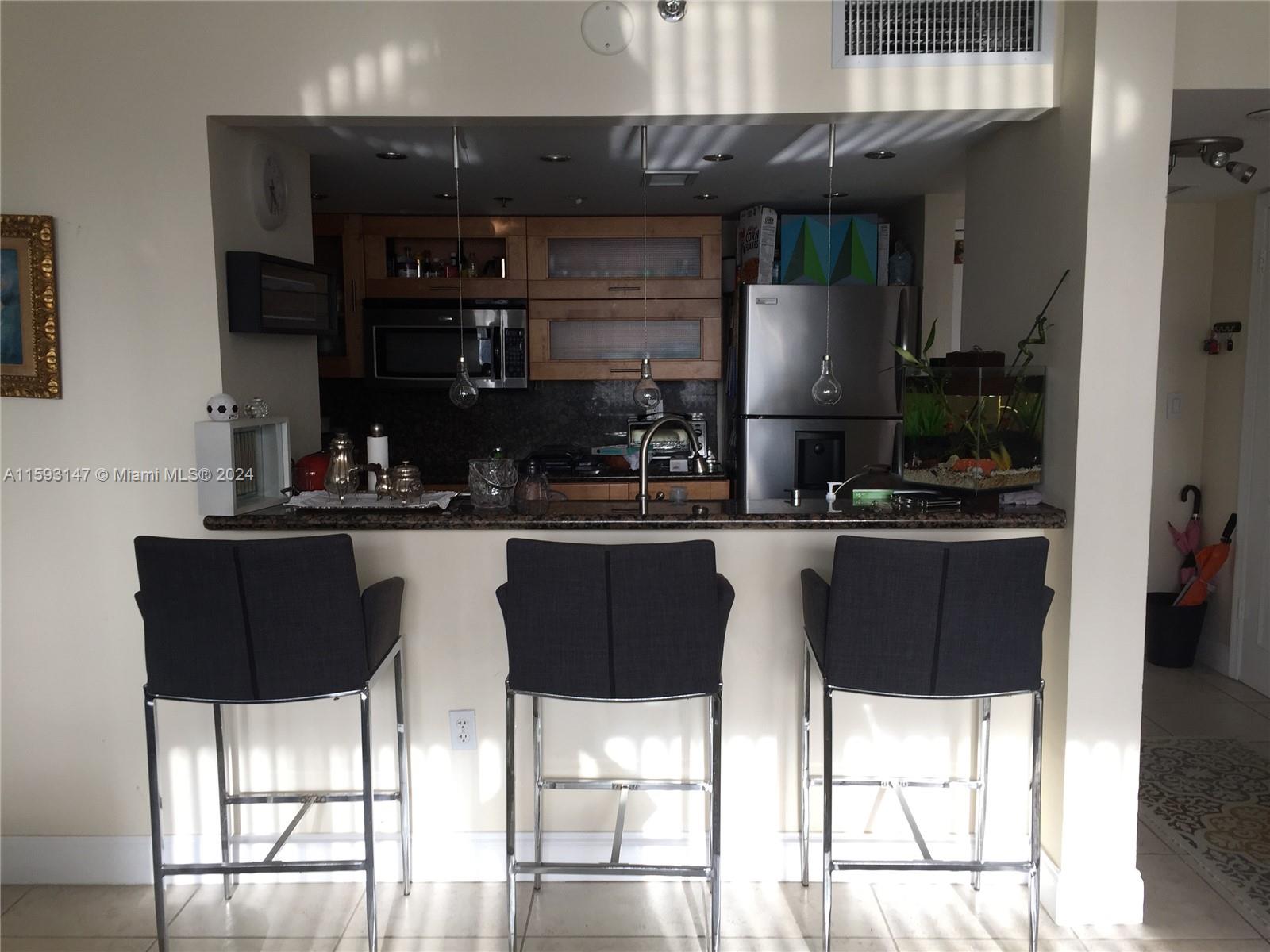 540 Brickell Key Drive, Unit 1511 Miami, FL 33131 - Photo 15 of 24 a kitchen with a sink and chairs