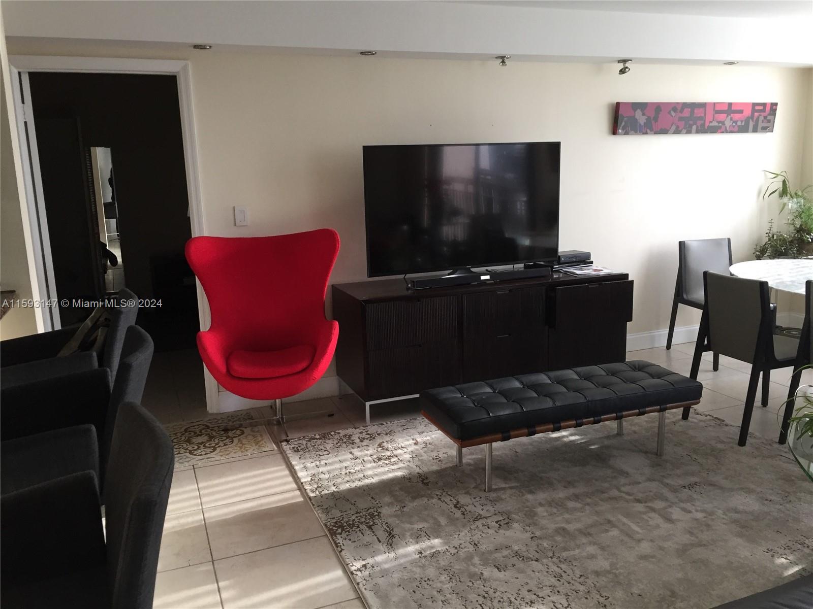540 Brickell Key Drive, Unit 1511 Miami, FL 33131 - Photo 16 of 24 a living room with furniture a flat screen tv and a refrigerator