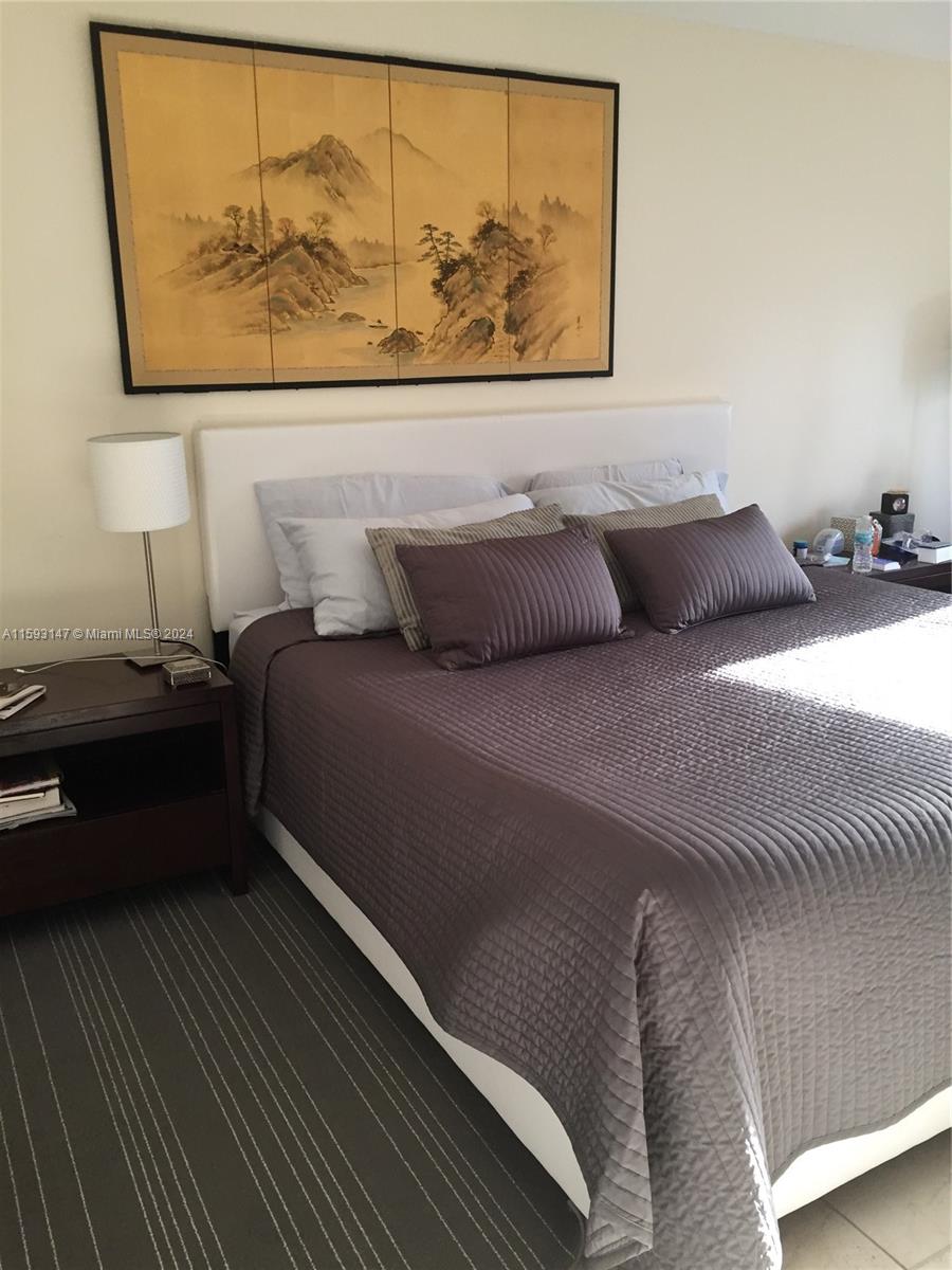 540 Brickell Key Drive, Unit 1511 Miami, FL 33131 - Photo 17 of 24 a bed sitting in a bedroom next to a wall with a painting on the wall