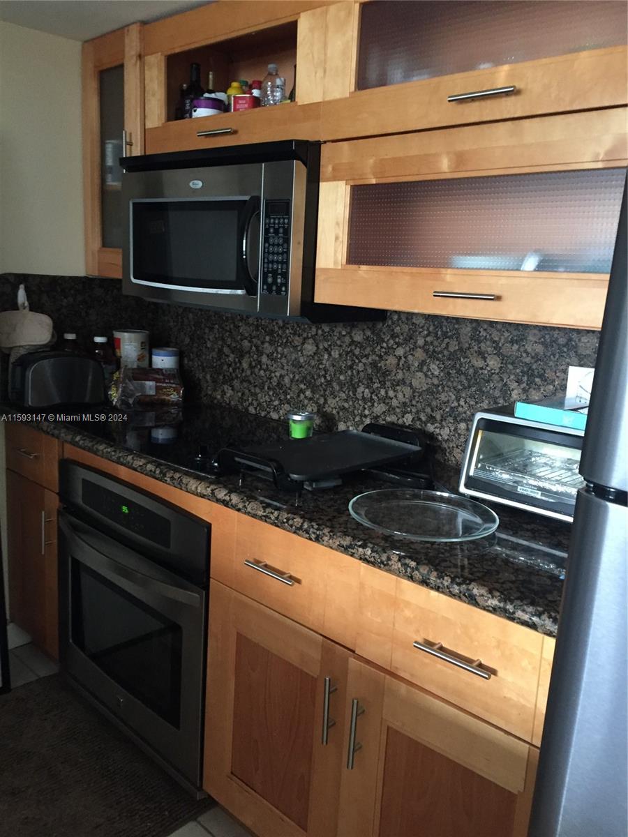 540 Brickell Key Drive, Unit 1511 Miami, FL 33131 - Photo 22 of 24 a kitchen with granite countertop stainless steel appliances a stove and a microwave