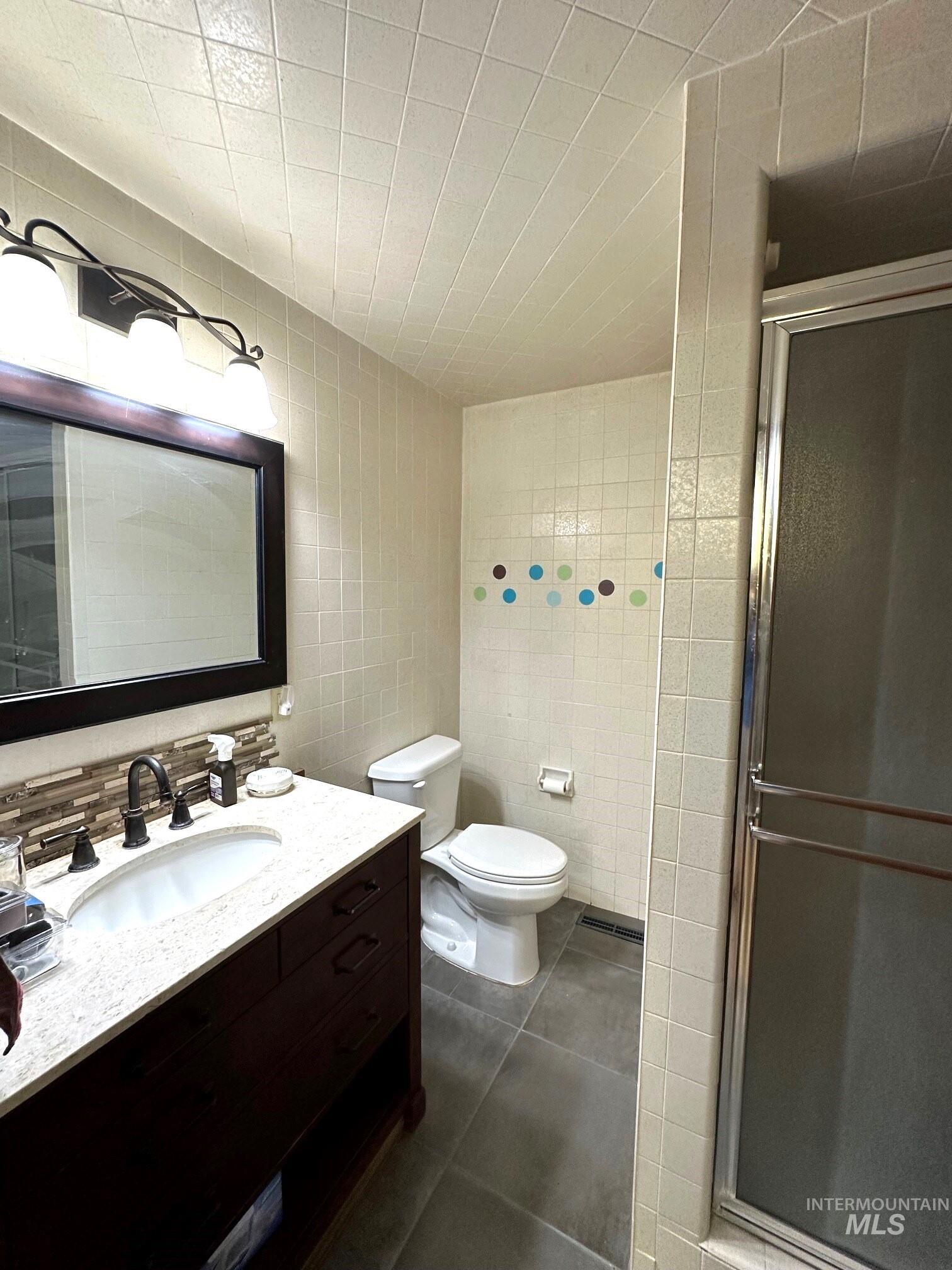 4436 Baker Road Ontario, OR 97914 - Photo 19 of 30 Bathroom with tile walls, vanity, a stall shower, and dark tile patterned flooring