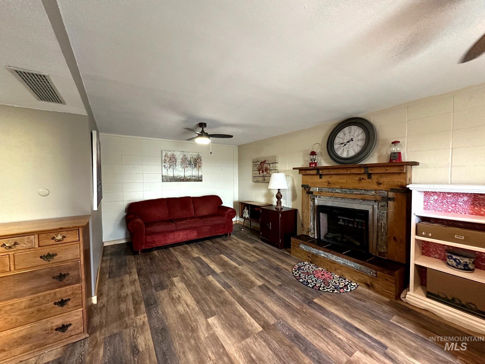 4436 Baker Road Ontario, OR 97914 - Photo 22 of 30 Living room featuring a ceiling fan, dark wood finished floors, a fireplace with raised hearth, and a textured ceiling