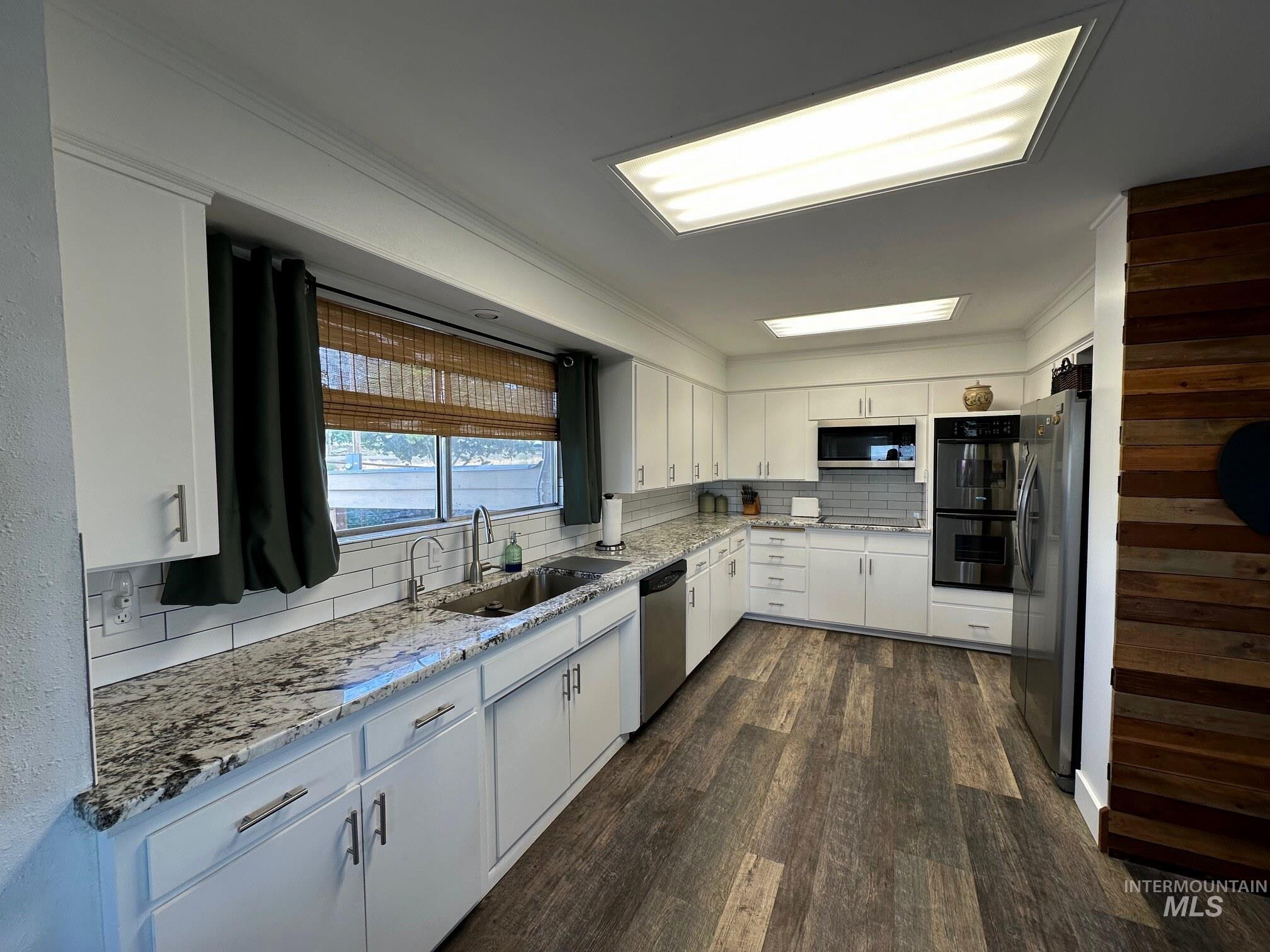 4436 Baker Road Ontario, OR 97914 - Photo 3 of 41 Kitchen featuring dark wood-type flooring, decorative backsplash, stainless steel appliances, white cabinetry, and light stone counters
