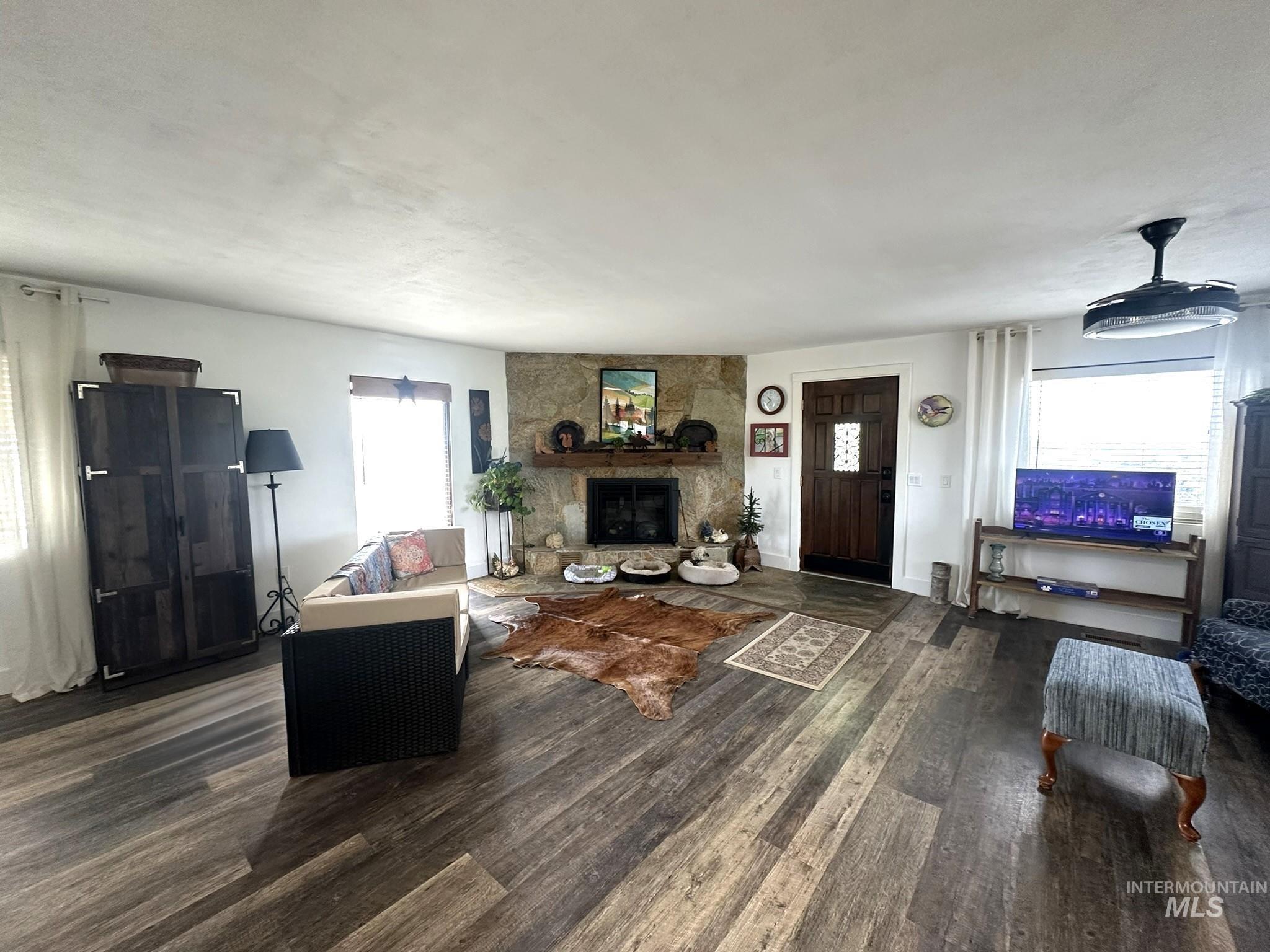 4436 Baker Road Ontario, OR 97914 - Photo 7 of 41 Spacious interior featuring wood-finish flooring, a stone fireplace with a substantial wood mantel, and multiple windows providing natural light