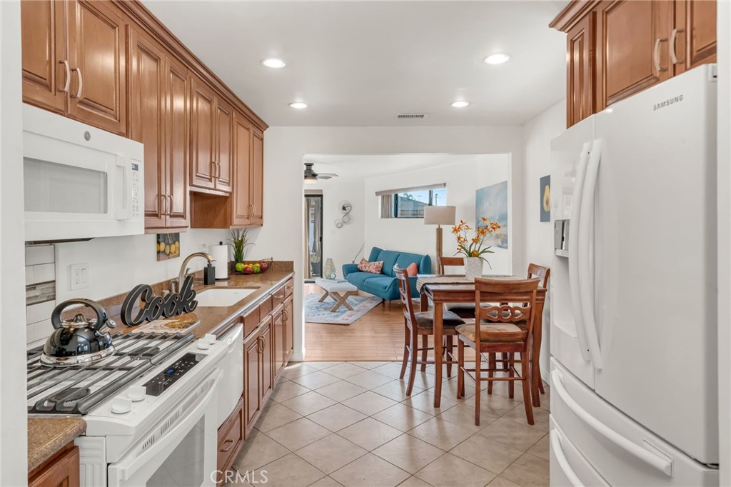 5142 West 142nd Street Hawthorne, CA 90250 - Photo 11 of 56 a kitchen with stainless steel appliances a stove a sink a oven a dining table and chairs with wooden floor