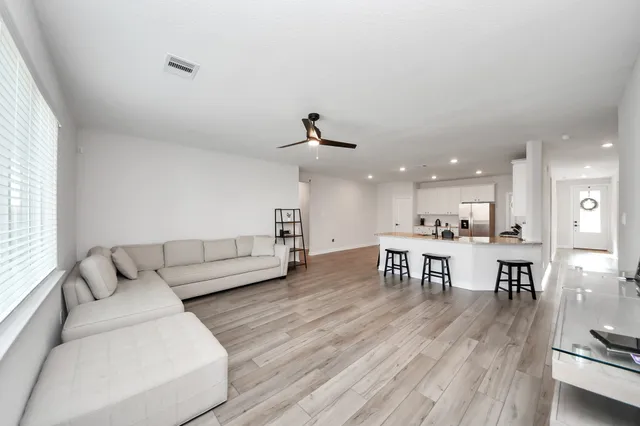 a living room with furniture and a dining table with wooden floor