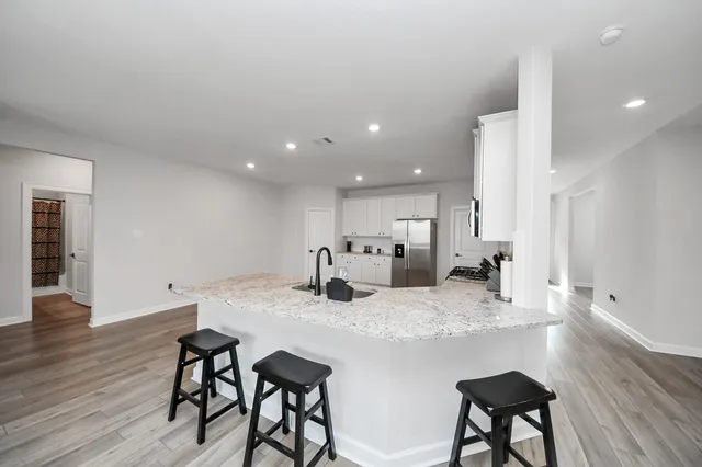 a kitchen with stainless steel appliances granite countertop a dining table chairs and wooden floor