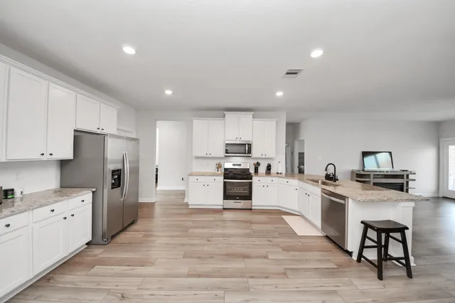 a large kitchen with stainless steel appliances granite countertop a stove oven and white cabinets