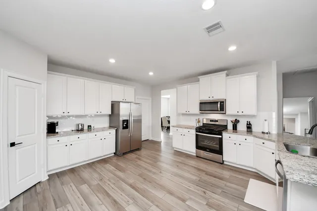 a kitchen with white cabinets and stainless steel appliances