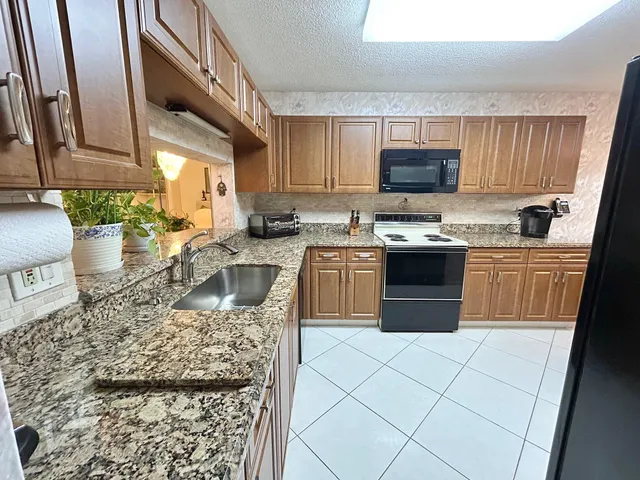 a kitchen with stainless steel appliances granite countertop a stove top oven sink and cabinets