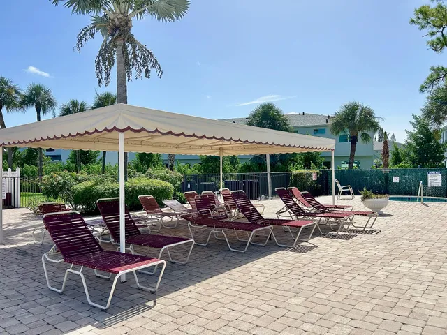 a view of a patio with a dining table and chairs under an umbrella with a barbeque