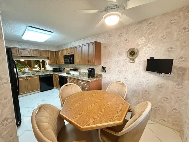 a living room with stainless steel appliances furniture a flat screen tv and kitchen view