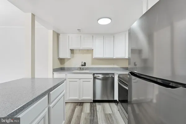 a kitchen with stainless steel appliances granite countertop a sink stove and white cabinets with wooden floor