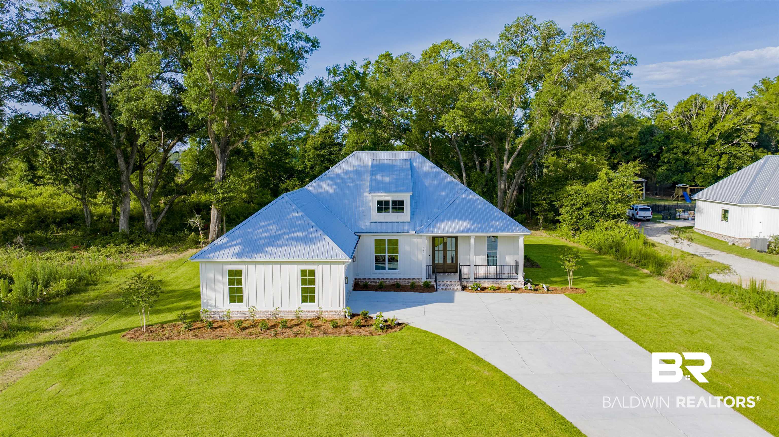 9275 Clarke Ridge Road Foley, AL 36535 - Photo 40 of 43 View of front of property with driveway, a metal roof, a front lawn, covered porch, and view of wooded area