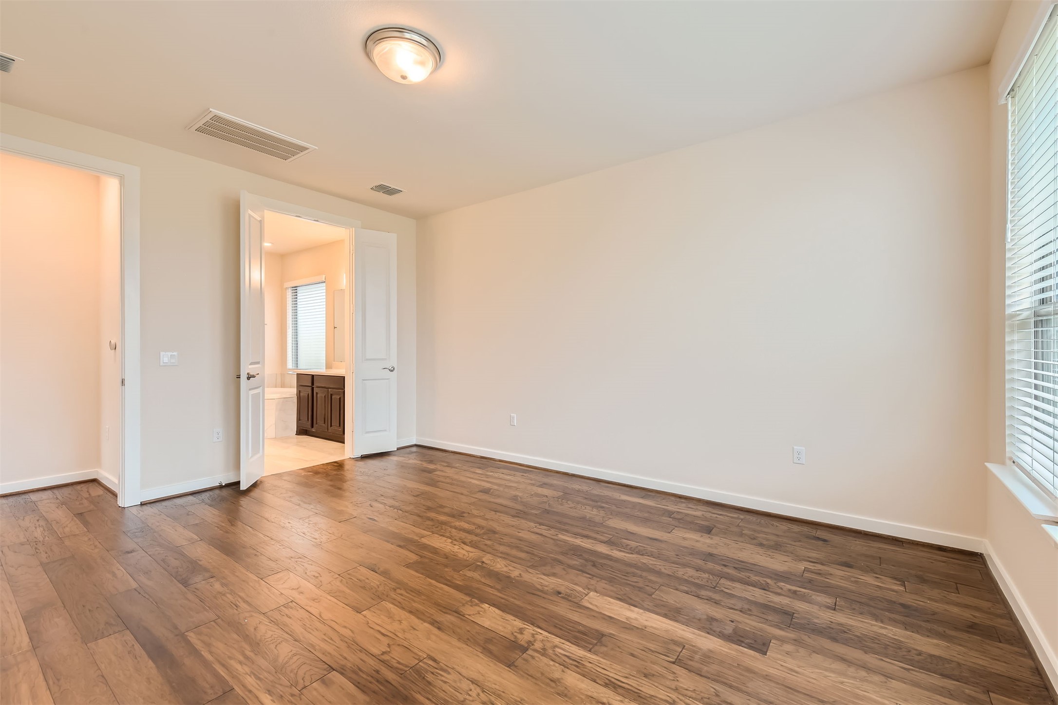 8313 Spire View Austin, TX 78744 - Photo 15 of 33 Rich hardwood floors extend through this open bedroom, leading to a connected bathroom.