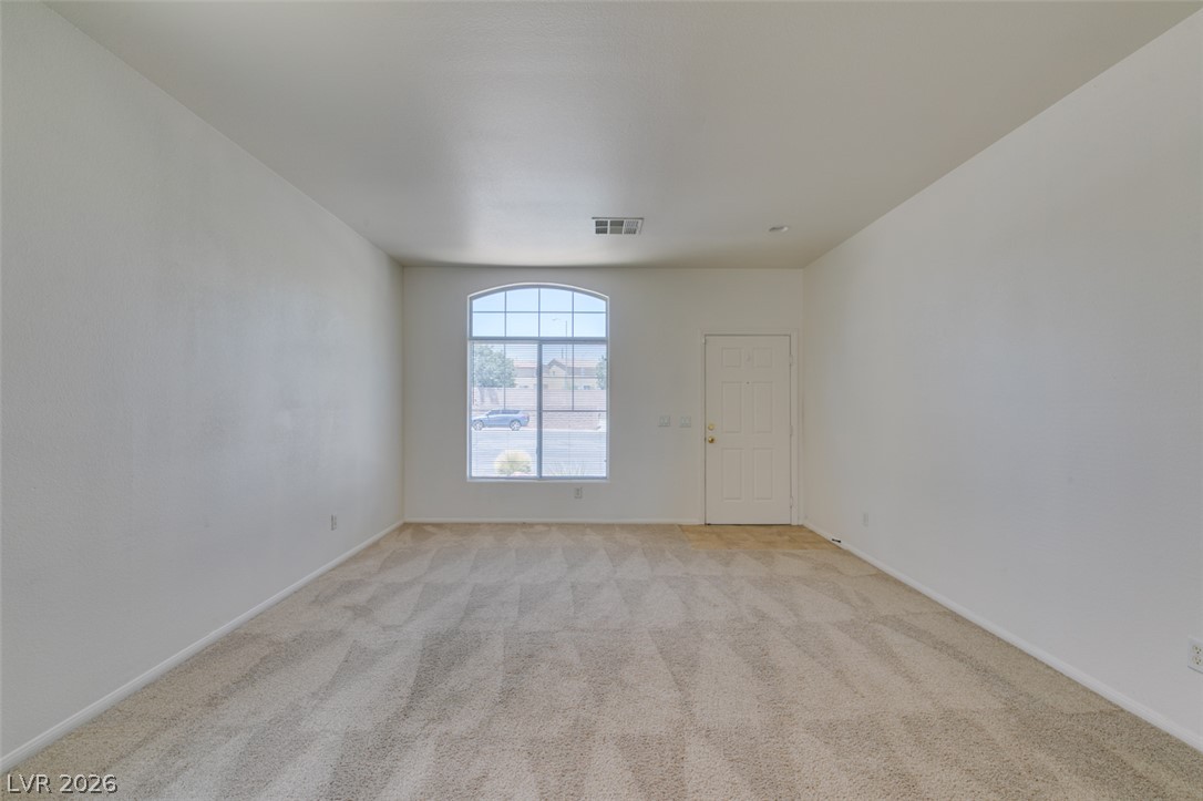 5150 Riverside Run Court North Las Vegas, NV 89081 - Photo 14 of 50 A sun-filled living area offers plush carpeting and a charming arched window, welcoming natural light.