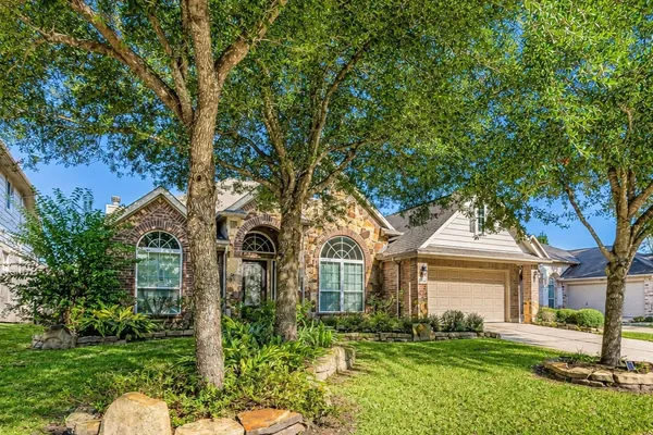 a front view of a house with a garden and trees