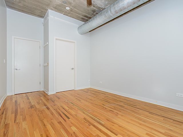 1151 West 15th Street, Unit 209 Chicago, IL 60608 - Photo 17 of 30 a bedroom with a bed and wooden floor
