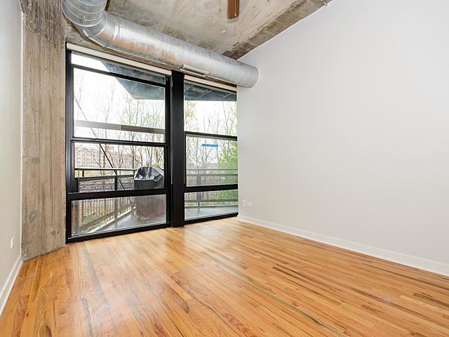 1151 West 15th Street, Unit 209 Chicago, IL 60608 - Photo 4 of 30 a view of an empty room with wooden floor and a window