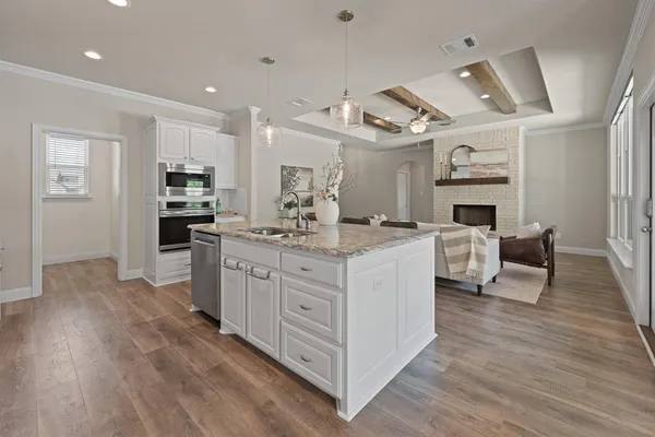 a large kitchen with kitchen island a white counter space a sink stainless steel appliances and cabinets