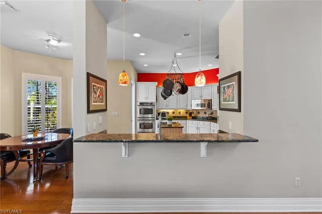 a kitchen with stainless steel appliances granite countertop a stove a sink dishwasher and white cabinets with wooden floor