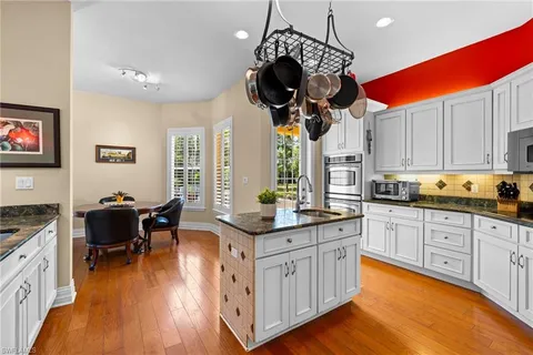 a kitchen with stainless steel appliances granite countertop a sink a stove and a wooden floors