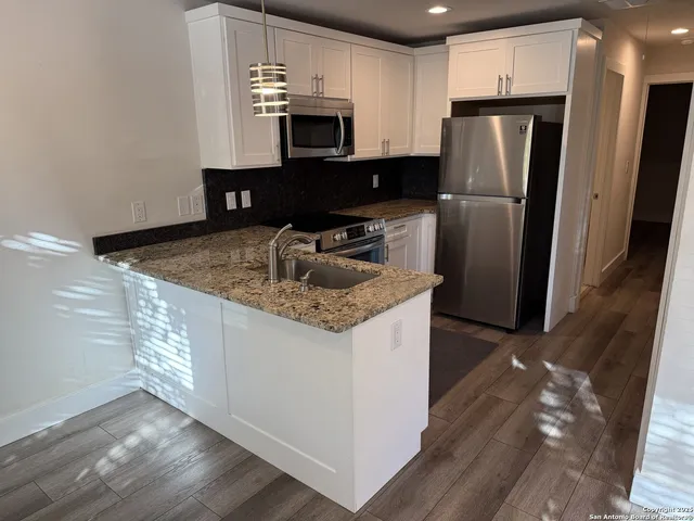 a kitchen with stainless steel appliances granite countertop a refrigerator a sink and a stove