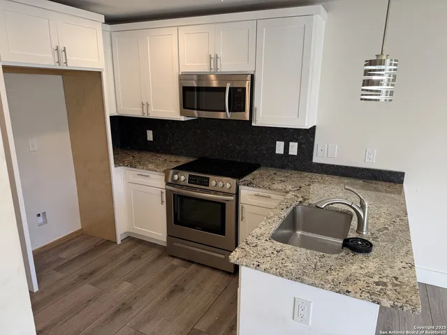 a kitchen with granite countertop a stove and a microwave with cabinets