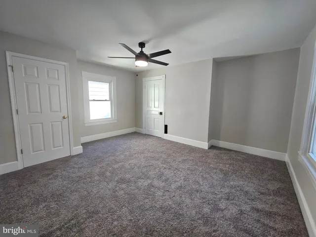 an empty room with a ceiling fan and window