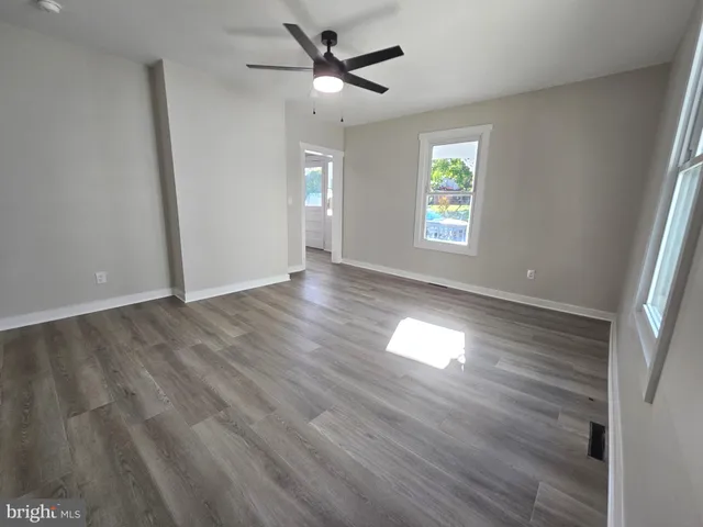 an empty room with wooden floor fan and windows