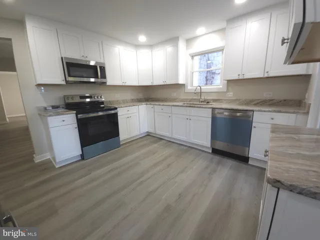 a kitchen with a sink dishwasher a refrigerator and wooden floor
