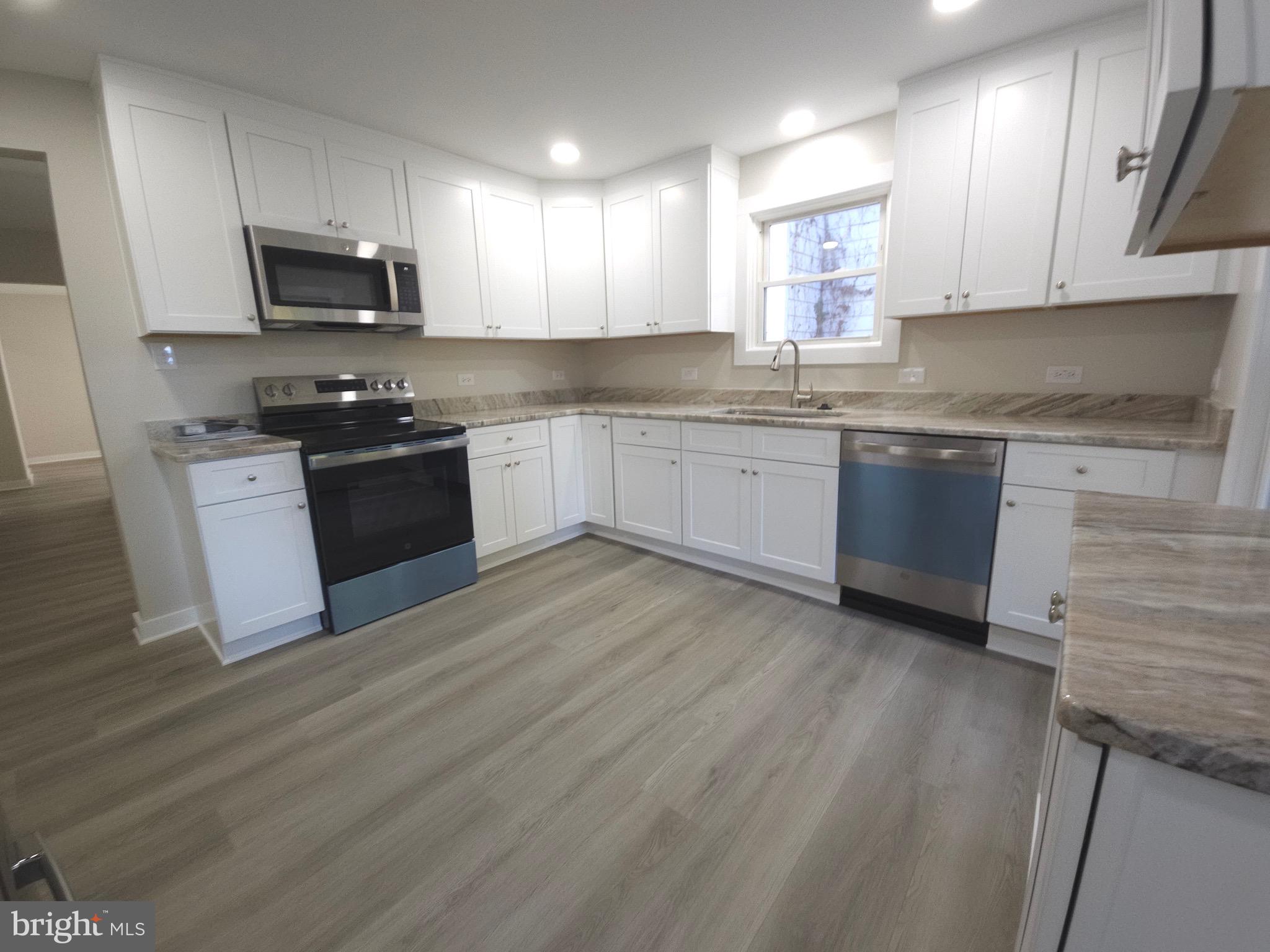 161 East Main Street Orange, VA 22960 - Photo 9 of 19 a kitchen with granite countertop a stove top oven a sink dishwasher and a microwave oven on the wooden floor