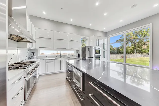 a large kitchen with stainless steel appliances granite countertop a lot of counter space and a sink